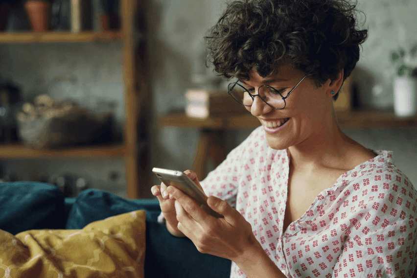 smiling woman using smartphone at home
