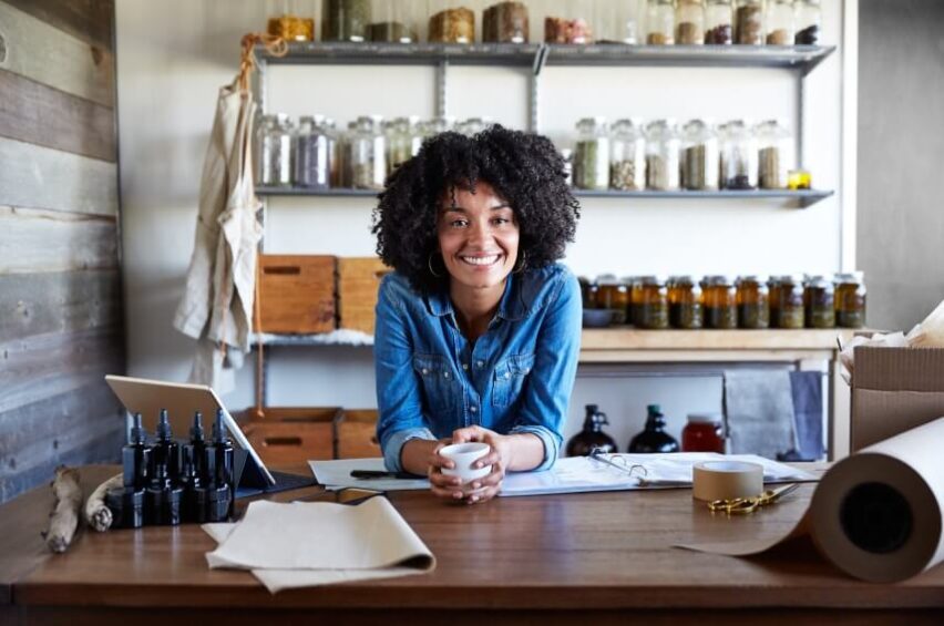 woman entrepreneur behind store counter, smiling at camera