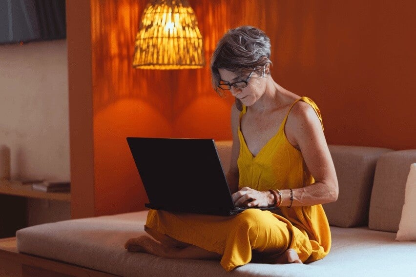 Woman seated on bed using laptop