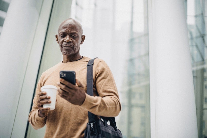 Man in front of city building looking at cell phone