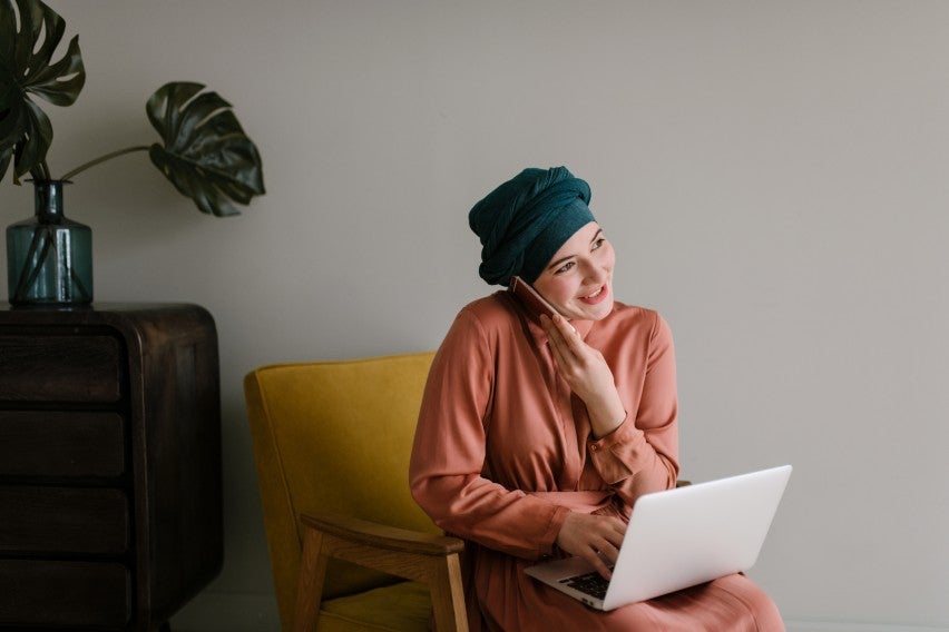 smiling woman on phone and laptop at home