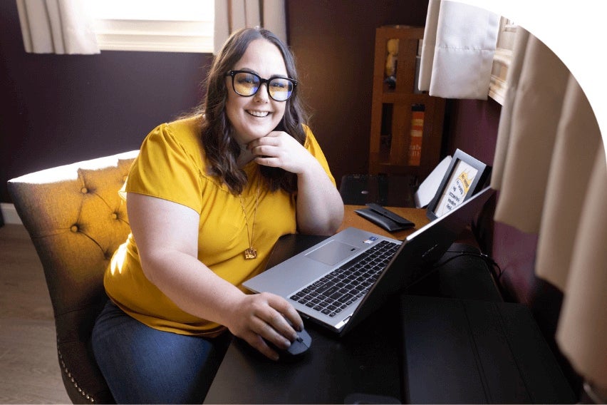 Lindsay Darby, CMA, smiling at camera, seated, with laptop