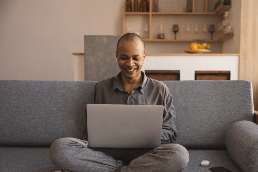 smiling person sitting on sofa with laptop open on lap