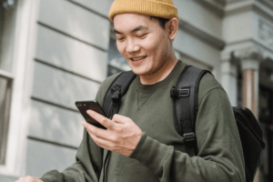 Man on street looking at phone smiling